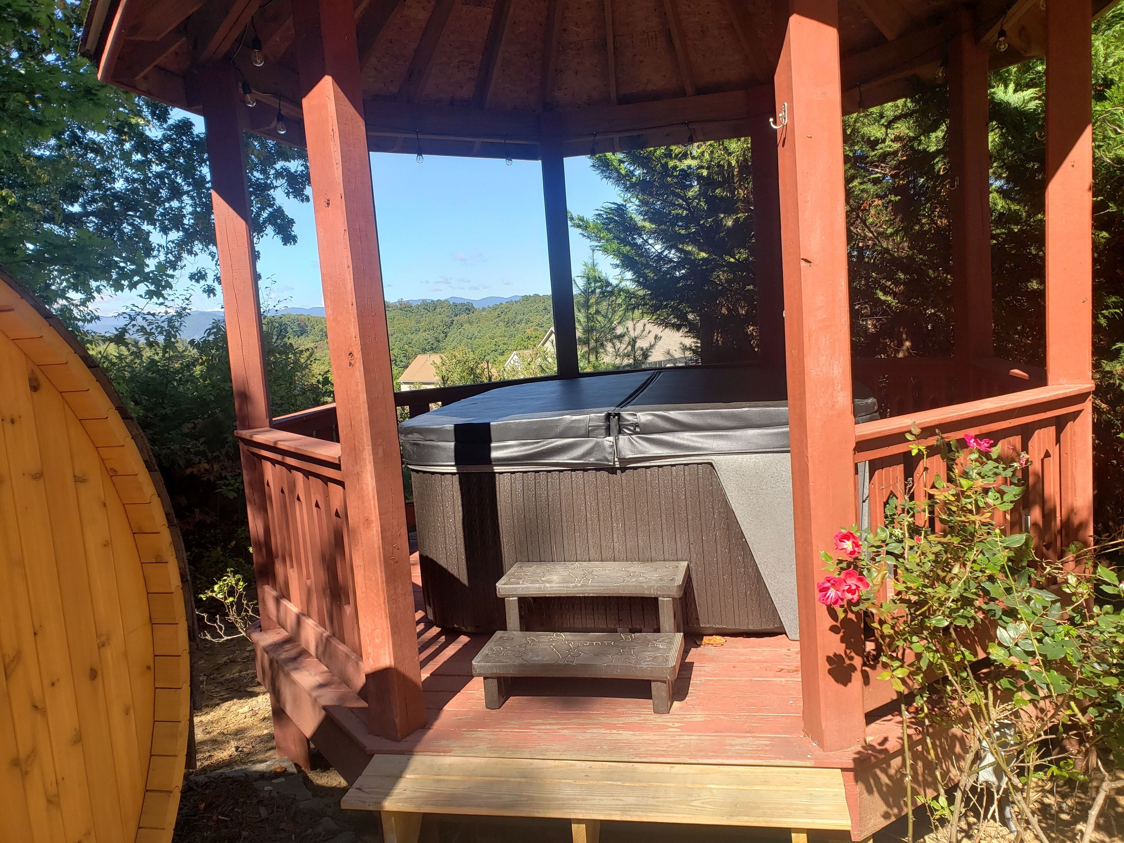 A wooden deck with a hot tub, a small table, and a bench.