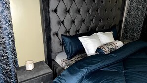 A bedroom with a tufted headboard, a bed with blue and white bedding, and a bedside table with a lamp.