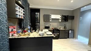 A modern kitchen with dark cabinets, a marble countertop, and a built-in oven.