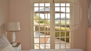 Ein Schlafzimmer mit großem Fenster, Nachttischlampe und Blick auf den Garten.