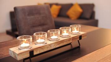 Ein Holztisch mit fünf Glaswindlichtern, jedes mit einer brennenden Kerze.