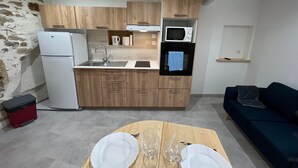 Une cuisine compacte équipée d’un réfrigérateur, d’un four à micro-ondes et d’un four traditionnel. On y trouve également une table à manger avec des assiettes et des verres.