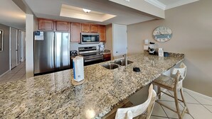 Una cocina moderna con encimeras de granito, electrodomésticos de acero inoxidable y armarios de madera.