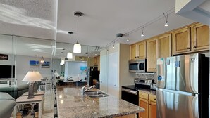 Eine moderne Küche mit Granit-Arbeitsplatten, Edelstahlgeräten, Holzschränken und Pendelleuchten.