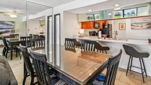 A modern kitchen with a central island, a dining area with a glass table, and a ceiling fan. - Edgewater Villa #2510 | Golf, Tennis, Beach! (Panama City Beach)