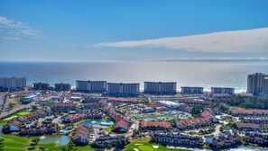 Un resort con varias edificaciones, un campo de golf y vista al mar.