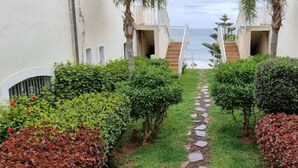 Ein Weg, der zu einem Strand mit weißen Gebäuden und Palmen führt.