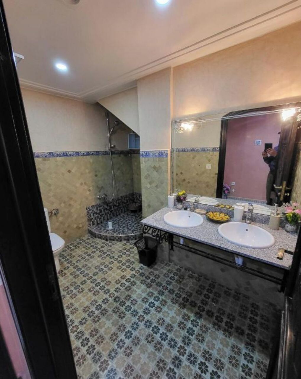 A bathroom with two sinks, a shower, and a large mirror.