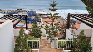 Ein Resort mit Poolbereich, Blick auf den Strand und einer Treppe, die zu den oberen Ebenen führt.