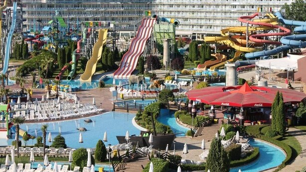 Un parc aquatique doté de nombreux toboggans et d’une piscine entourée de chaises longues et de parasols.