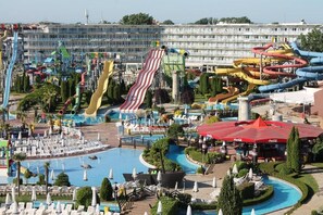 A water park with multiple slides and a swimming pool surrounded by lounge chairs and umbrellas.