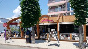 Un restaurant avec une terrasse, un panneau de signalisation et un vélo.