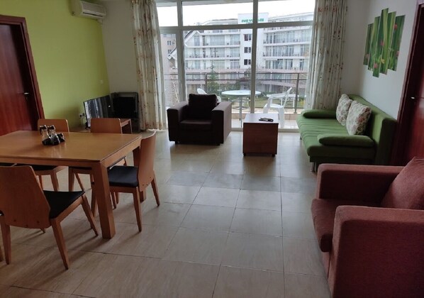 A living room with a dining table, chairs, a sofa, and a coffee table.
