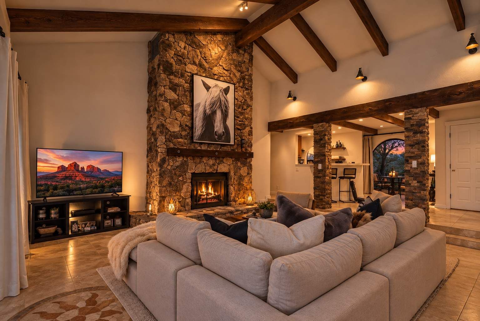 A living room with a stone fireplace, a large sofa, a television, and a stone wall.