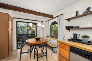 A kitchen with a wooden dining table, chairs, a built-in oven, and a dishwasher.