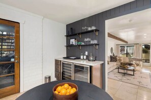 A modern kitchen with a black countertop, a wooden bowl of oranges, and a built-in wine rack.