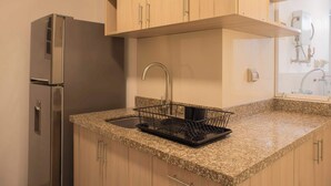 Una cocina con encimeras de granito, refrigerador de acero inoxidable y armarios de madera.