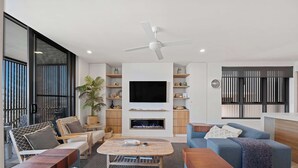 Ein modernes Wohnzimmer mit Fernseher, Deckenventilator und Kamin.