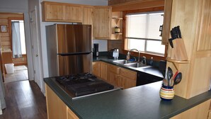 A kitchen with wooden cabinets, a stainless steel refrigerator, a gas stove, and a sink.