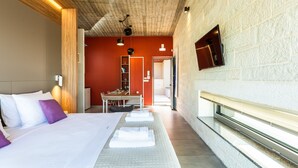 A hotel room with a large bed, a wooden ceiling, a red accent wall, and a view of the hallway. - Aori villa (Apokoronas)