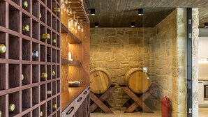 A wine cellar with wooden racks, wine barrels, and a red fire hydrant. - Aori villa (Apokoronas)
