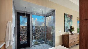 A modern bathroom with a glass-enclosed shower, stone wall, and a wooden vanity. - Hula House: Luxury Villa w/ Superb Views/Amenities (Koloa)