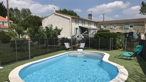 A swimming pool with a white border, surrounded by artificial grass, and two lounge chairs. - A peaceful, restful little corner (Annezay)