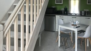 A modern kitchen with a dining area, a staircase, and a green wall. - A peaceful, restful little corner (Annezay)