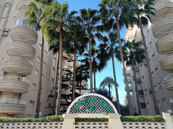 A multi-story building with balconies and palm trees.
