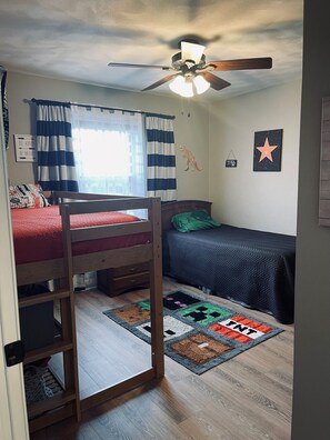 A bedroom with two bunk beds, a ceiling fan, a star wall decoration, and a motivational poster.