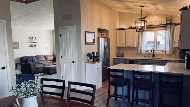 A modern kitchen with a central island, white cabinets, and a dining area with a wooden table and chairs. - Oshkosh EAA AirVenture Rental (Oshkosh)