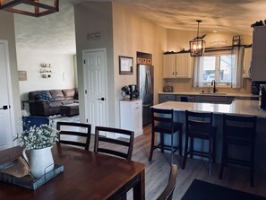 A modern kitchen with a central island, white cabinets, and a dining area with a wooden table and chairs.