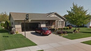 A two-story house with a garage, a driveway, and a well-maintained lawn. - Oshkosh EAA AirVenture Rental (Oshkosh)