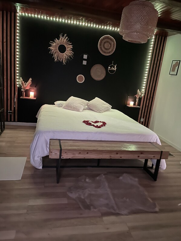 A bedroom with a bed, wooden bench, decorative wall art, and string lights.