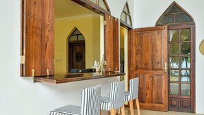 Een kamer met een houten bar, streepstoelen en een groot rondboogvenster.