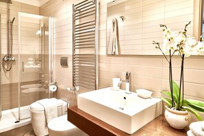 Une salle de bain moderne avec une douche en verre, un grand lavabo blanc et une orchidée en pot.