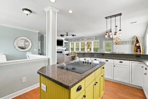 A kitchen with a central island, white cabinets, and a yellow accent wall. - Sunny Side Up - Beautiful OKI beach home on cul-de-sac.  Short walk to beach. (Oak Island)