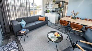 Ein modernes Wohnzimmer mit grauem Sofa, Couchtisch und Essbereich mit Holztisch und Stühlen.