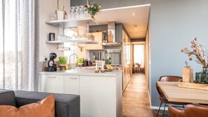 Eine moderne Küche mit weißen Schränken, einer zentralen Kochinsel und einem Essbereich mit Holztisch und Stühlen.