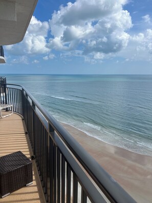 A balcony with a view of the ocean and a sandy beach. - The pool is open!  Come have your best vacation ever! (Daytona Beach)
