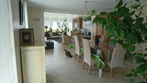 A dining area with a table, chairs, and a cat. - Stone house 300 m from the beach (Plouguerneau)