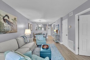 A modern living room with a sofa, a coffee table, and a dining area with chairs and a table. - Relaxation in Paradise! (Key Largo)