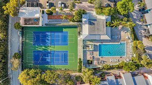 Luchtbeeld van een pand met een tennisbaan, een zwembad en een parkeerplaats.