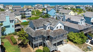 A coastal residential area with houses, a visible swimming pool, and a clear view of the ocean.