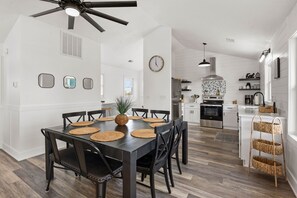 A modern kitchen with white cabinetry, a black stove, and a hanging light fixture.
