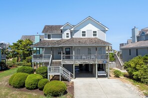A two-story house with a front porch, a covered deck, and a staircase leading to the upper level.