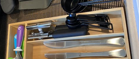 A drawer with neatly organized kitchen utensils including spoons, forks, knives, and a grater.