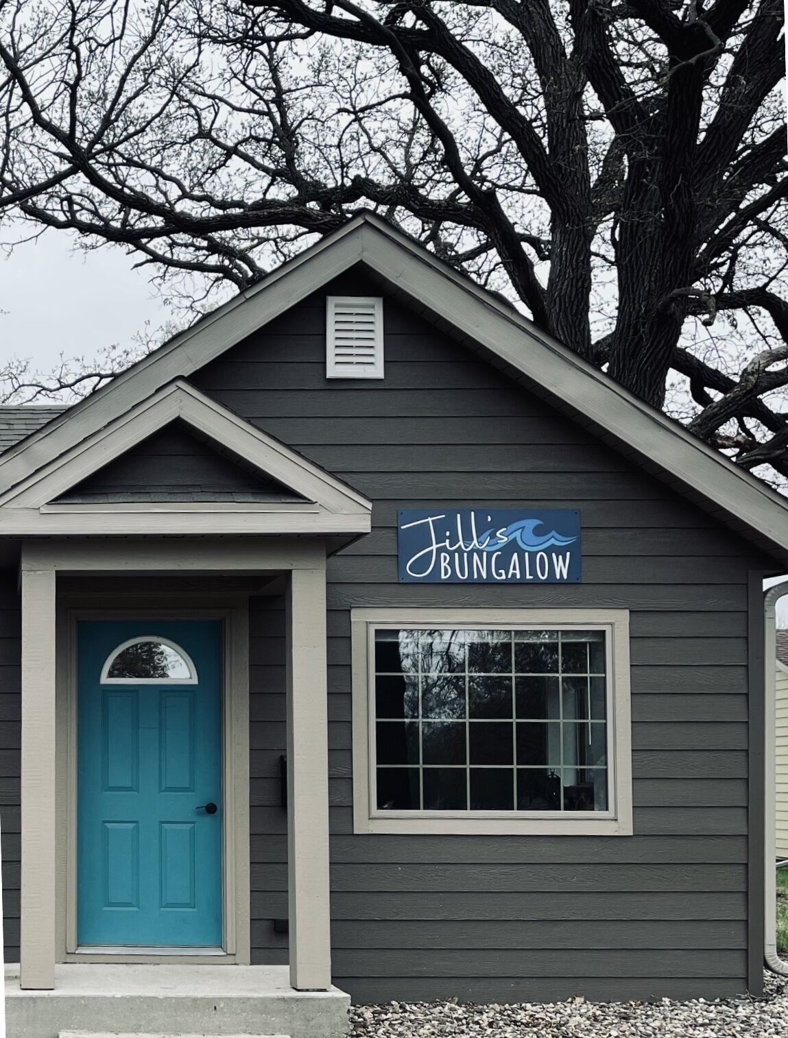 En lille bygning med en blå dør og et skilt, der står "Jill's Bungalow".