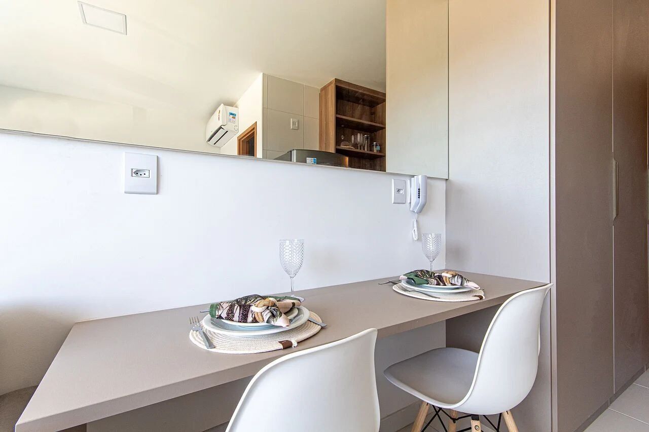 Un espace de salle à manger moderne avec une longue table, deux chaises et un grand miroir.