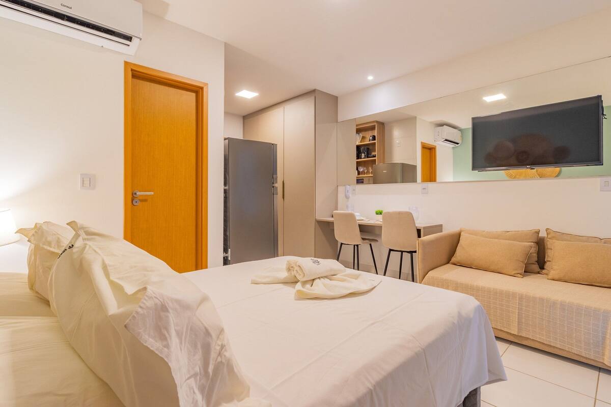 Une chambre d’hôtel comprenant un lit, un canapé, un bureau avec une chaise, un téléviseur à écran plat et un coin cuisine.